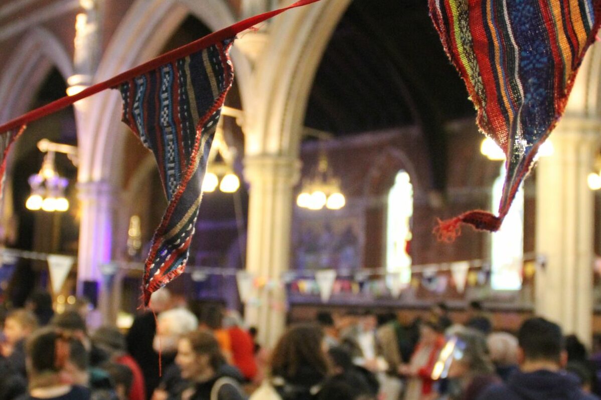 A church filled with people celebrating, adorned with colourful bunting.
