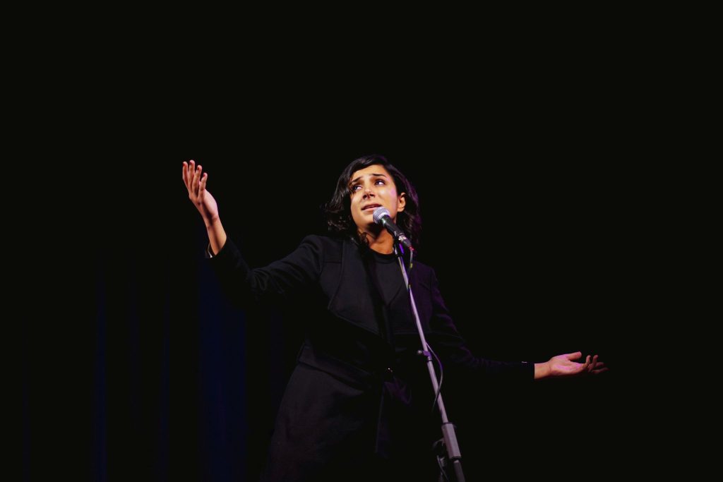 a woman standing on a stage with her hands up
